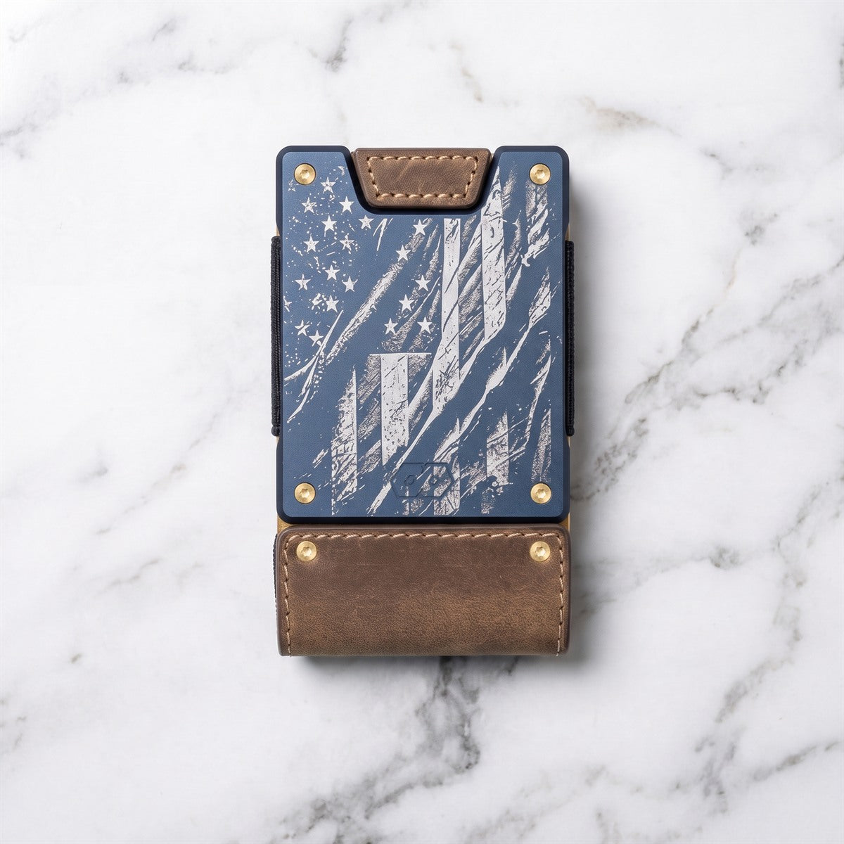 A slim wallet or card holder with a blue American flag design and brown leather trim, photographed from above on a white marble surface.