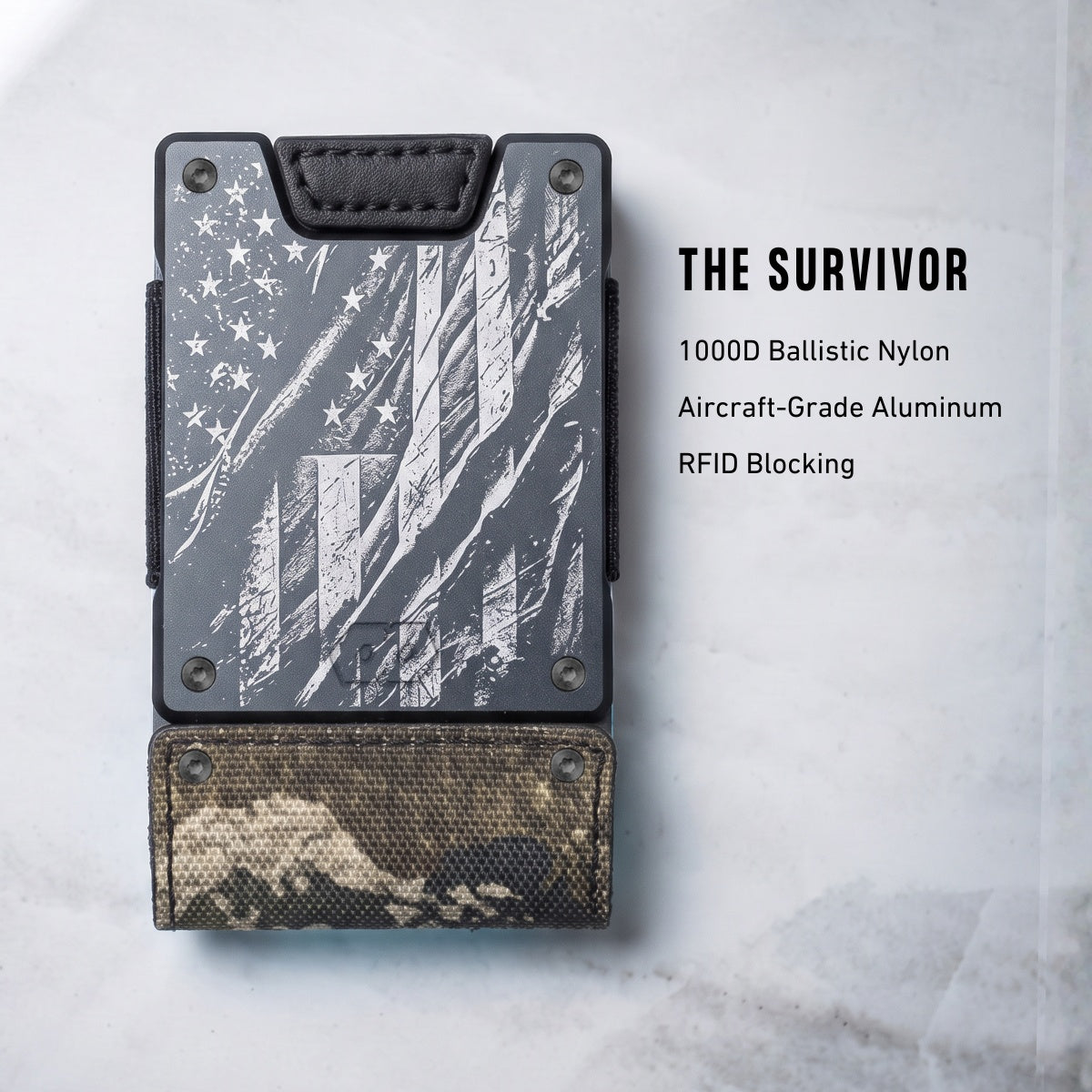 A slim rectangular wallet or card holder shown on a light stone-like background with text reading 'THE SURVIVOR' and material callouts. The product has a dark gray distressed American flag print on the upper section and a brown/tan camouflage pattern on the lower section, with black trim and metal rivets.