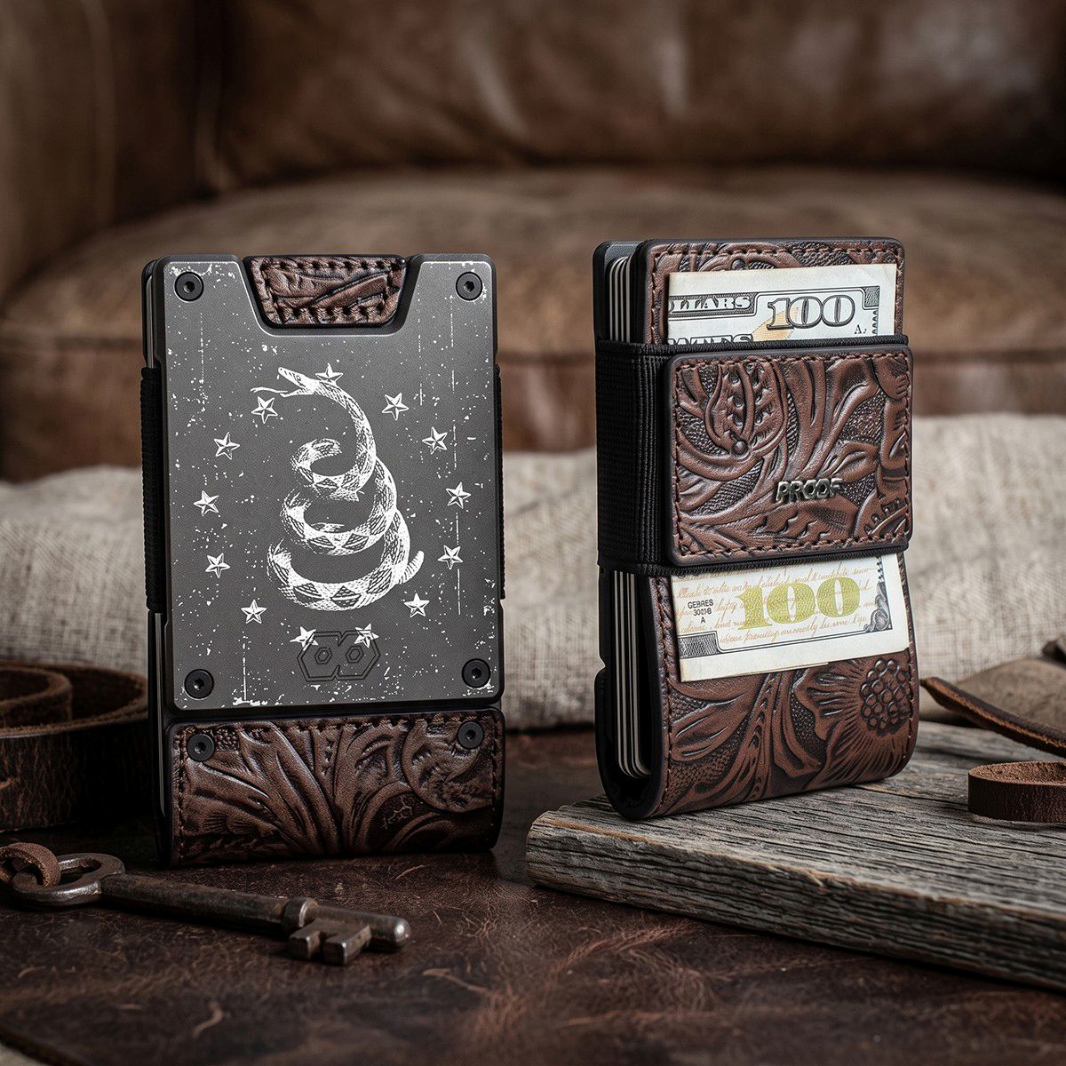 Two wallets on a leather couch, one showing the Gadsden snake engraving and the other showing tooled brown leather with cash tucked inside.